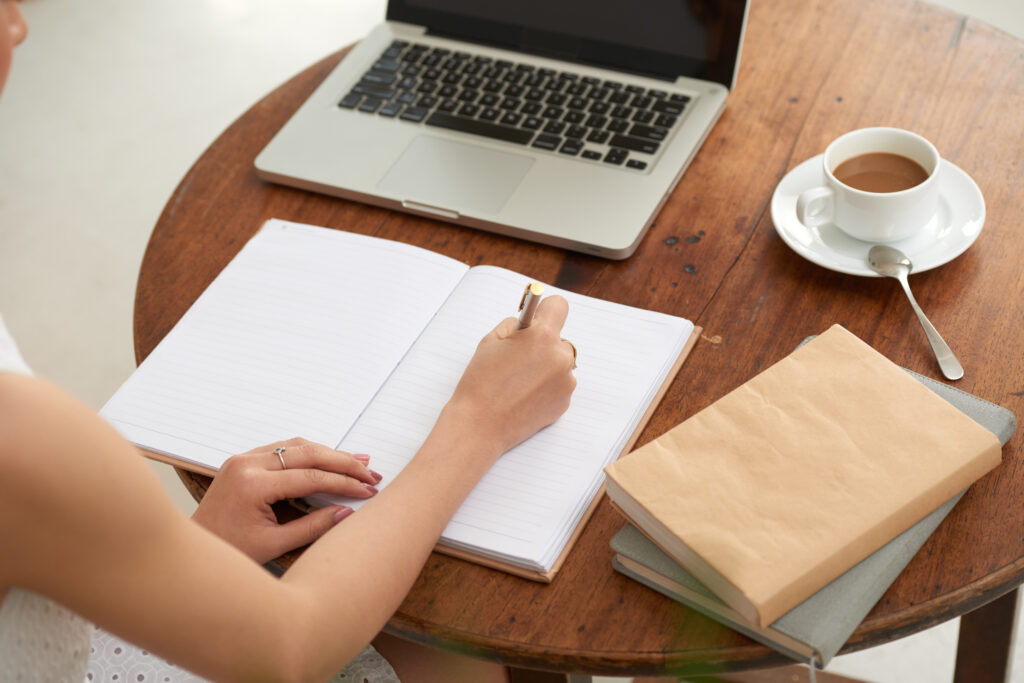 Female student writing notes in her textbook when sitting in cafe